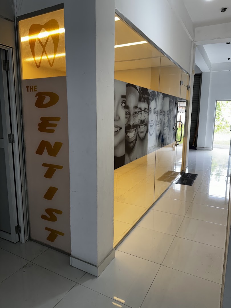 Amber-lit glass entrance corridor with THE DENTIST name and smiling faces mural
